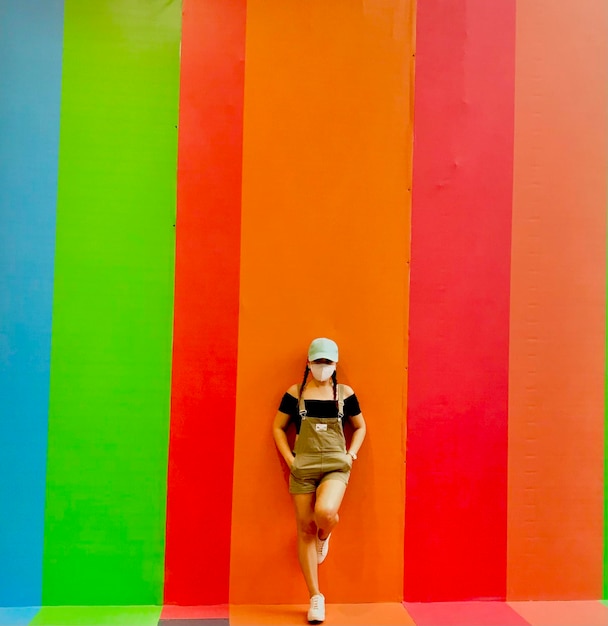 Foto vista trasera de una mujer de pie contra una pared amarilla