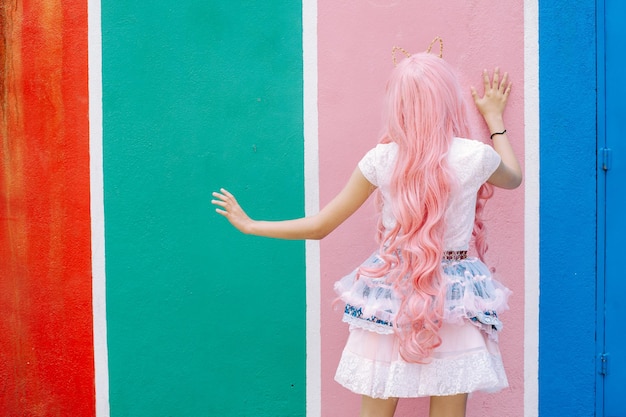 Vista trasera de una mujer de pie contra una pared de color