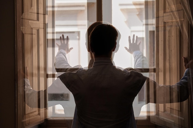 Vista trasera de una mujer de pie contra la ventana