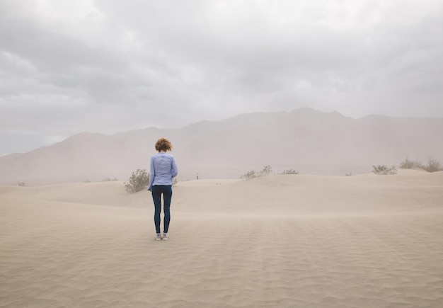 Foto vista trasera de una mujer de pie en el desierto