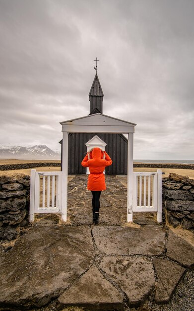 Foto vista trasera de una mujer de pie fuera de la iglesia contra el cielo