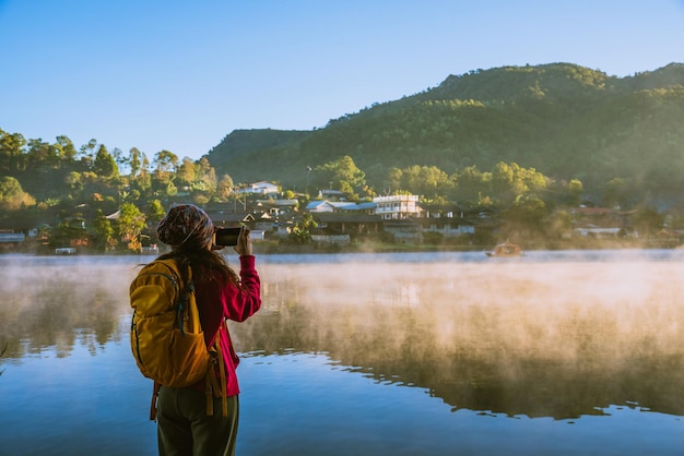 Foto vista trasera de una mujer de pie junto al lago contra el cielo