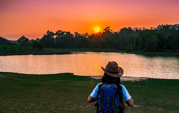 Foto vista trasera de una mujer de pie junto al lago durante la puesta de sol