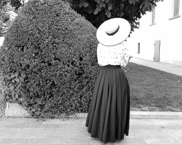 Foto vista trasera de una mujer de pie junto a un árbol