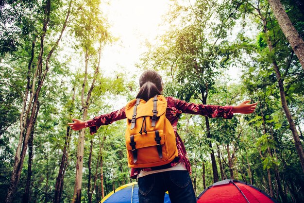 Foto vista trasera de una mujer de pie junto a los árboles en el bosque