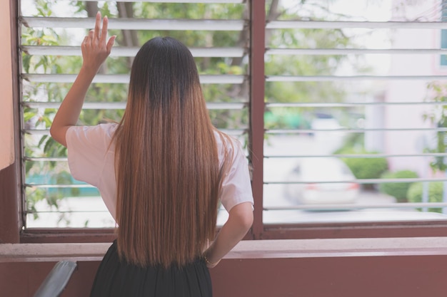 Foto vista trasera de una mujer de pie junto a la ventana