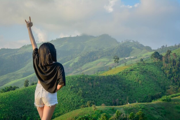 Foto vista trasera de una mujer de pie en la montaña contra un cielo nublado