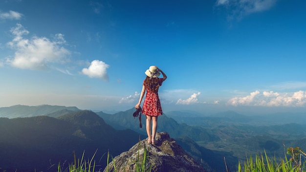 Vista trasera de una mujer de pie en la montaña contra el cielo