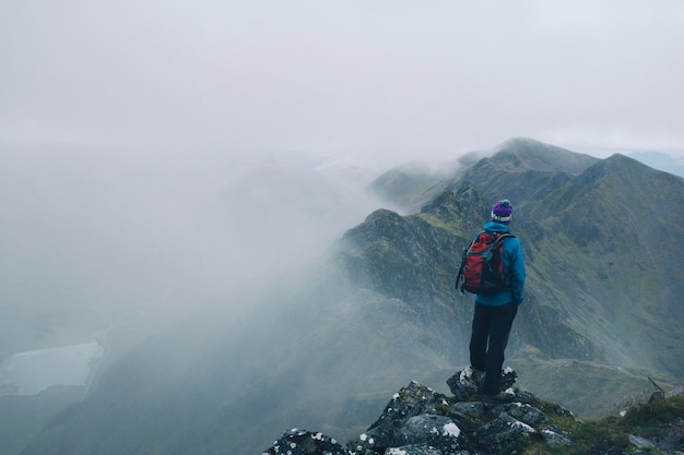 Vista trasera de una mujer de pie en la montaña durante el tiempo de niebla