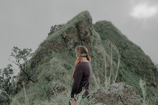 Foto vista trasera de una mujer de pie en la montaña