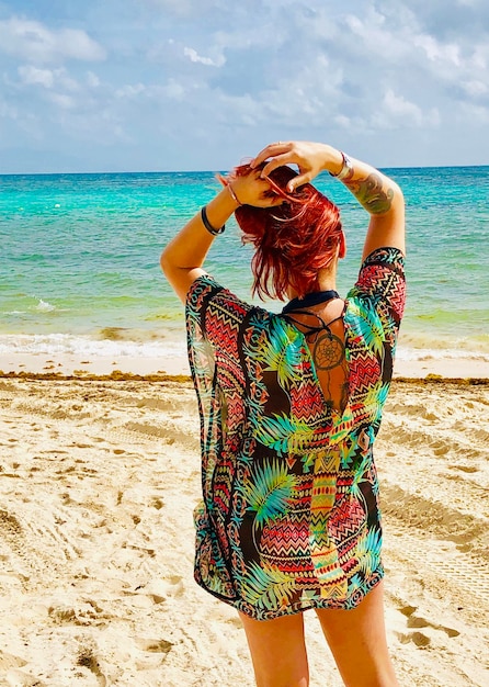 Foto vista trasera de una mujer de pie en la playa