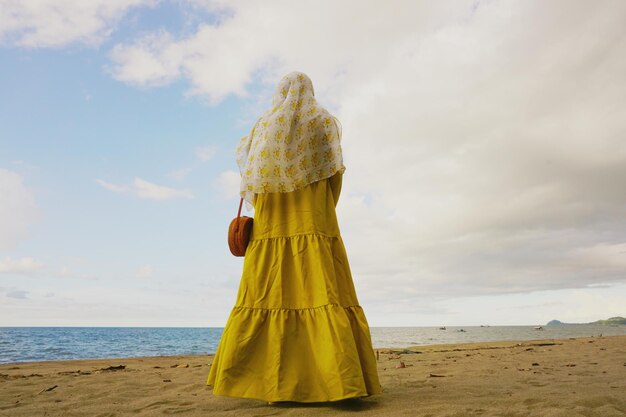 Foto vista trasera de una mujer de pie en la playa