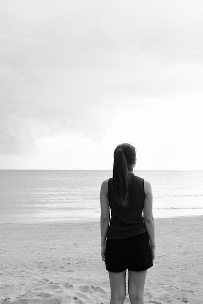 Foto vista trasera de una mujer de pie en la playa