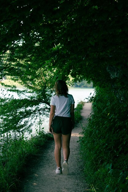 Vista trasera de una mujer de pie en un sendero entre plantas