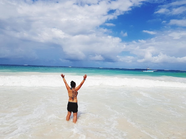 Foto vista trasera de una mujer en la playa contra el cielo