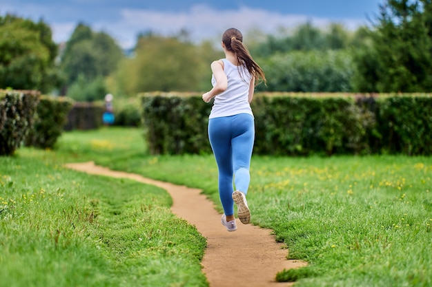 Vista trasera de la mujer que está entrenando en el parque en ropa deportiva