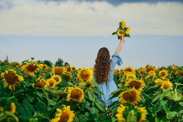 Vista trasera de una mujer con ramo de girasoles en la mano