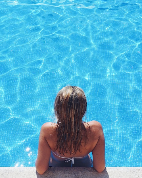 Foto vista trasera de una mujer relajándose en la piscina