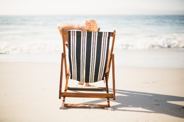 Vista trasera de una mujer relajante en la playa