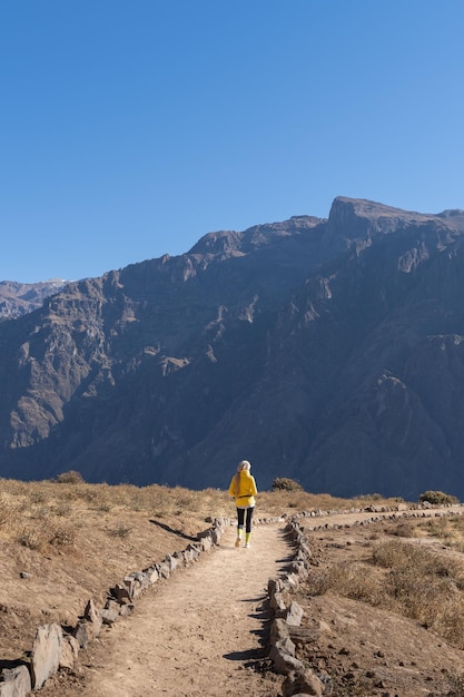 Vista trasera de una mujer rubia caminando por el Cañón del Colca en el sur de Perú