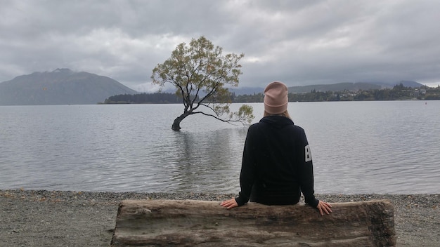 Vista trasera de una mujer sentada en un asiento junto al lago