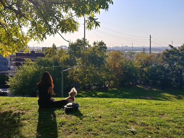 Foto vista trasera de una mujer sentada en un campo de hierba