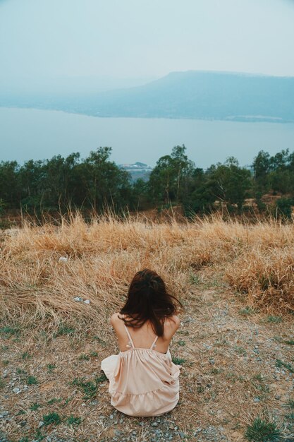 Foto vista trasera de una mujer sentada en el campo