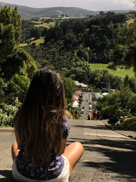 Foto vista trasera de una mujer sentada en la carretera