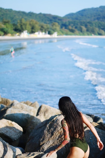 Foto vista trasera de una mujer sentada en la playa contra el cielo