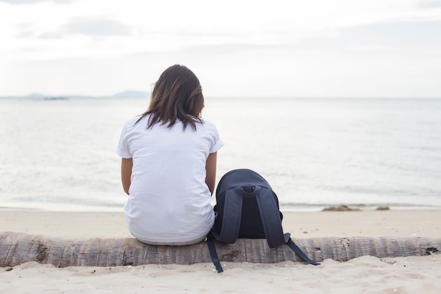 Foto vista trasera de una mujer sentada en la playa