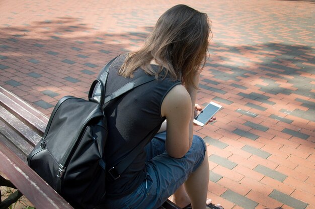 Foto vista trasera de una mujer sentada en un teléfono móvil