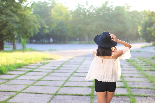 Vista trasera de una mujer con sombrero de pie contra los árboles