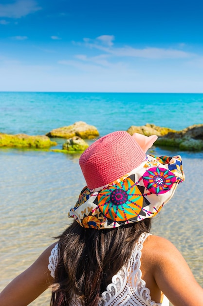 Foto vista trasera de una mujer con sombrero en la playa