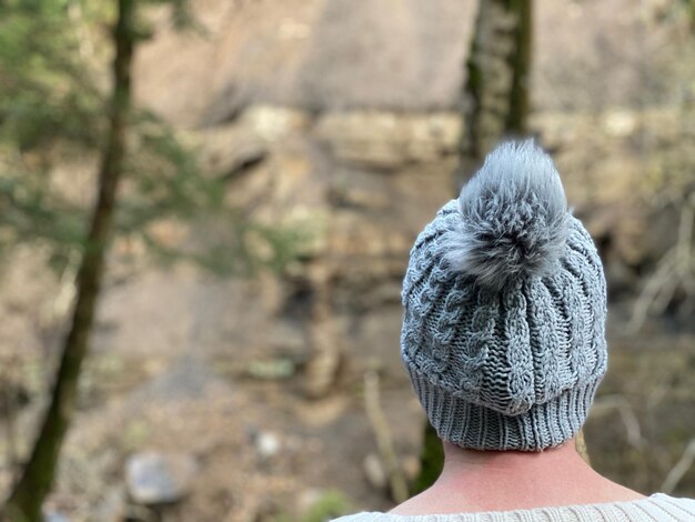 Foto vista trasera de una mujer con un sombrero de punto caminando por el bosque