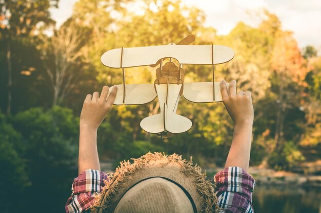 Foto vista trasera de una mujer sosteniendo un avión modelo en el parque