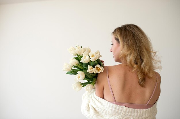 Vista trasera de una mujer sosteniendo un ramo de tulipanes blancos Vestido de comodidad Día de San Valentín