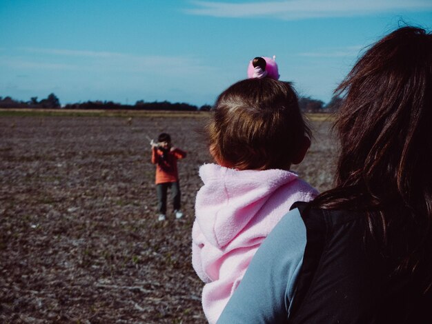 Foto vista trasera de una mujer con su hija y su hijo de pie en tierra