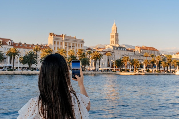 Foto vista trasera de una mujer tomando fotos de la ciudad de split en croacia