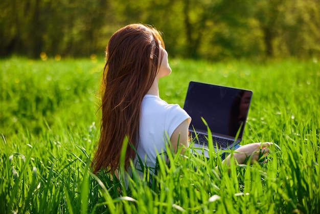 Vista trasera de una mujer usando una tableta digital en el campo