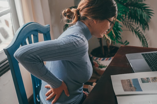 Vista trasera de una mujer usando una tableta digital mientras está sentada en el sofá en casa