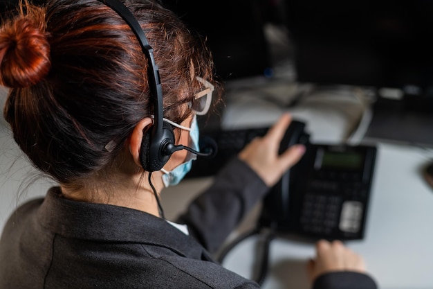 Foto vista trasera de una mujer usando un teléfono fijo