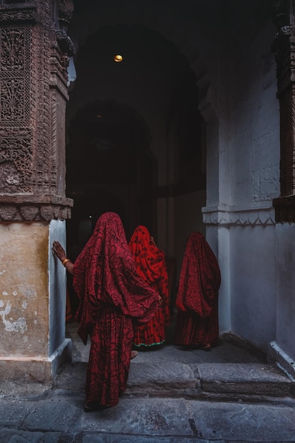 Vista trasera de mujeres de pie con ropa tradicional roja en el templo