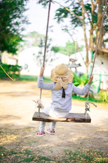 Foto vista trasera de una niña en el columpio en el patio de recreo