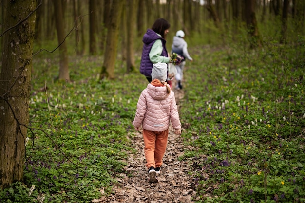 Vista trasera de la niña y la madre caminando por el sendero del bosque Concepto de ocio de primavera al aire libre