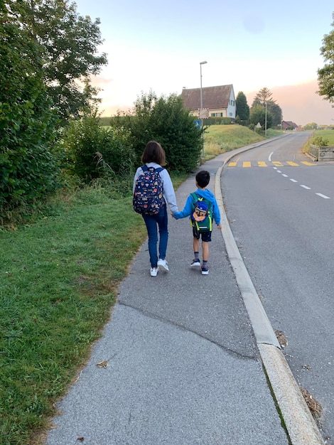 Foto vista trasera de una niña y un niño caminando por la carretera