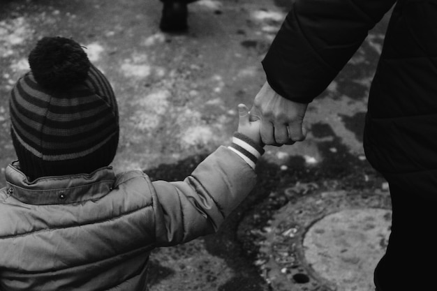 Foto vista trasera de la niña sosteniendo las manos de la madre