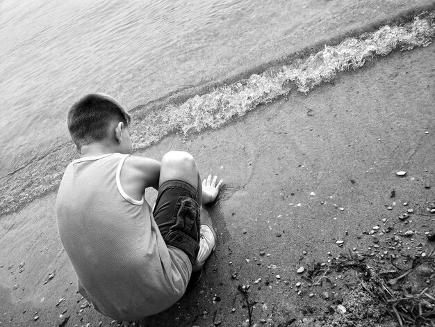 Foto vista trasera de un niño agachado en la playa