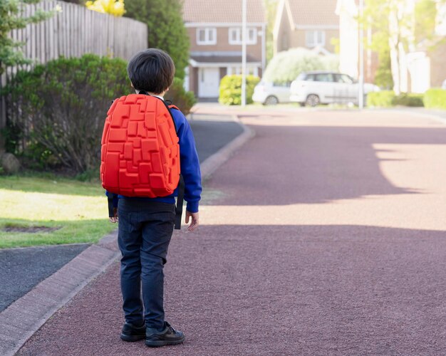 Foto vista trasera de un niño caminando por la carretera en la ciudad