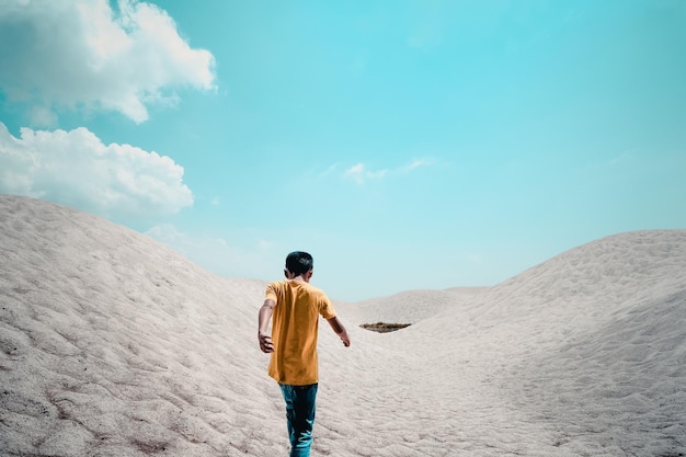 Vista trasera de un niño caminando en el desierto contra el cielo azul