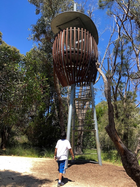 Foto vista trasera de un niño caminando por una estructura metálica contra el cielo